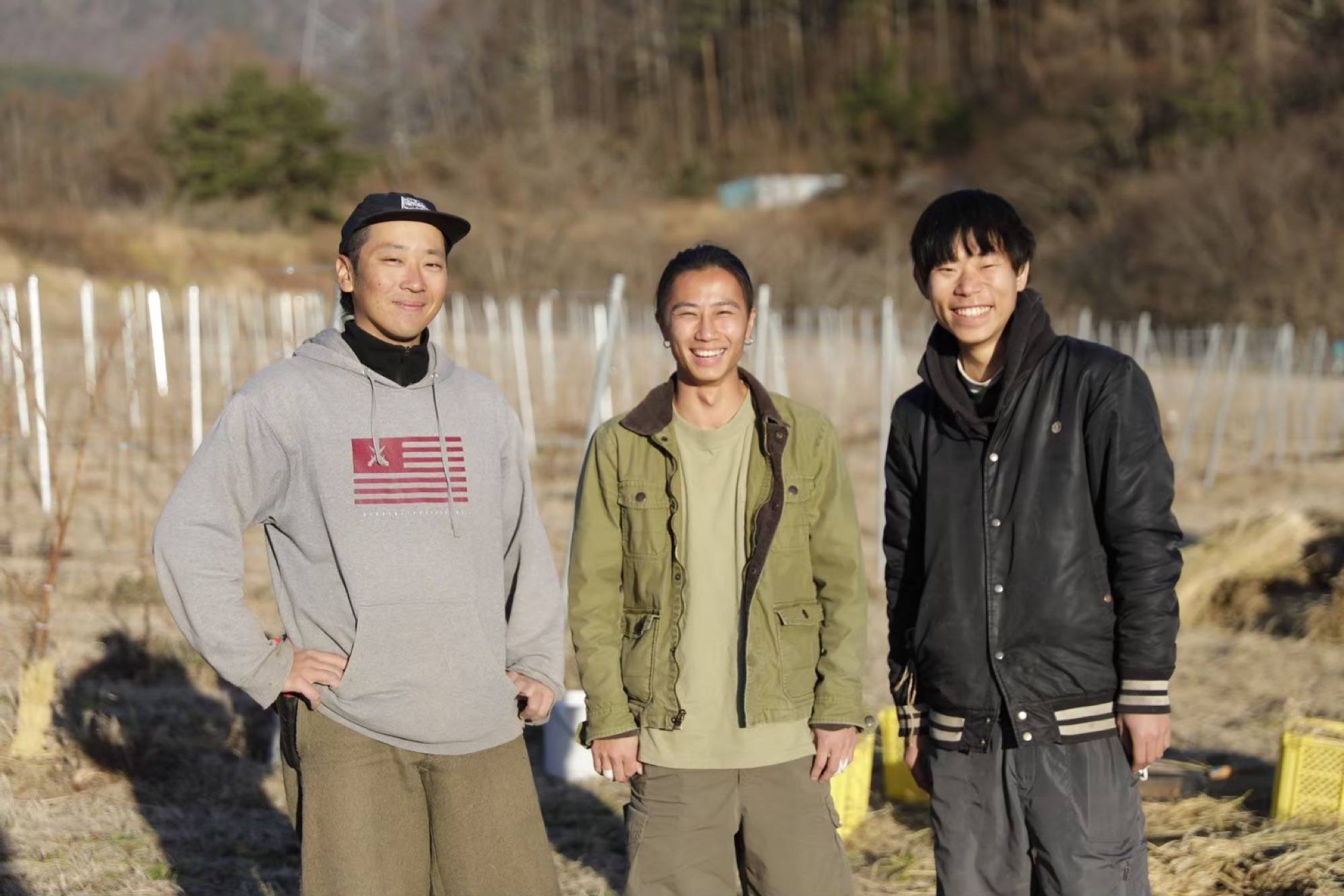 冬の畑に立つ、ノーマンズのメンバー3人